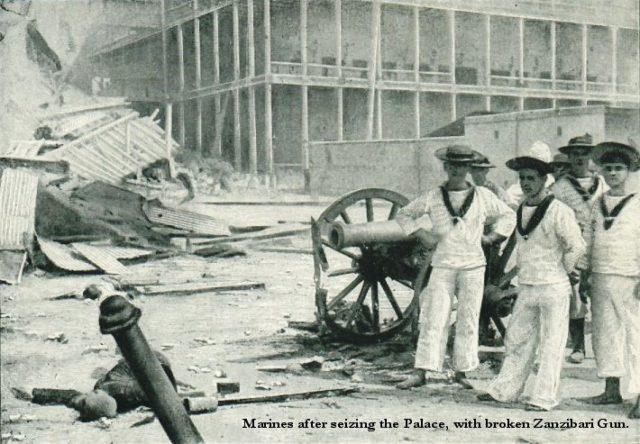 Os marinheiros britânicos posam com um canhão capturado fora do palácio do sultão após a Guerra Anglo-Zanzibar.