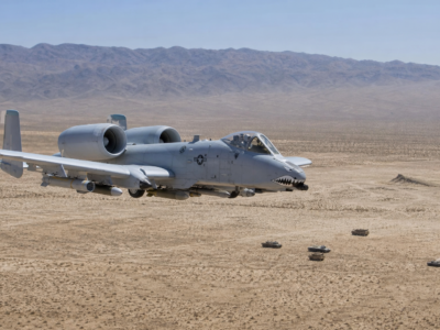 A-10 Thunderbolt II voando baixo sobre área de treinamento desértica sem combate ativo.