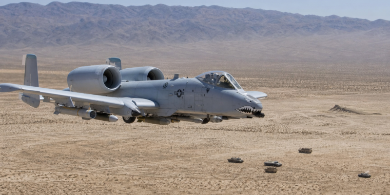 A-10 Thunderbolt II voando baixo sobre área de treinamento desértica sem combate ativo.