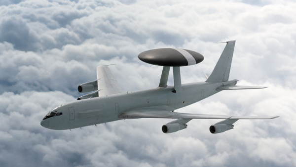 Avião AWACS em voo com radar circular sobre a fuselagem acima das nuvens