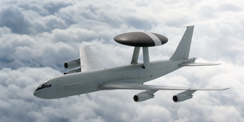 Avião AWACS em voo com radar circular sobre a fuselagem acima das nuvens