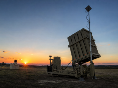 Bateria moderna de defesa aérea em terreno aberto ao entardecer, representando o sistema Iron Dome de forma educativa