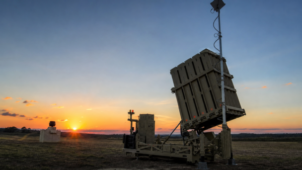 Bateria moderna de defesa aérea em terreno aberto ao entardecer, representando o sistema Iron Dome de forma educativa