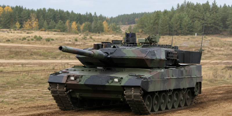Tanque Leopard 2 em campo de treinamento europeu cercado por árvores
