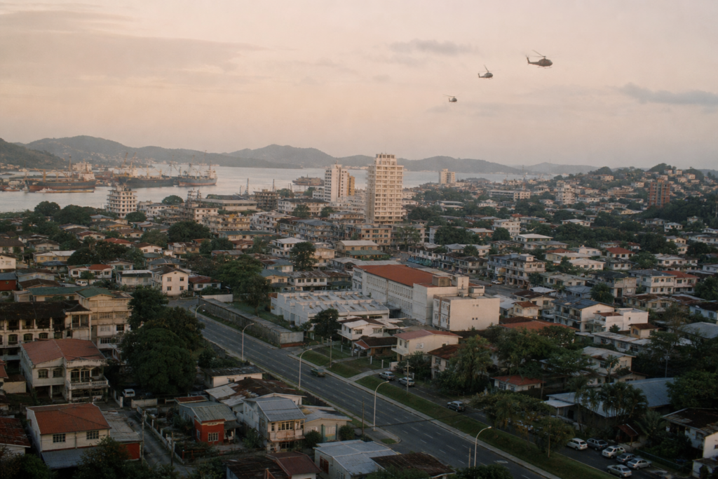 Vista urbana do Panamá no fim dos anos 1980 com helicópteros militares ao longe durante a Operação Just Cause