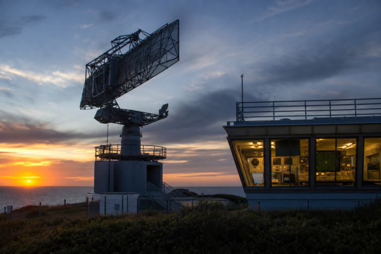 Antena de radar militar em base costeira ao pôr do sol