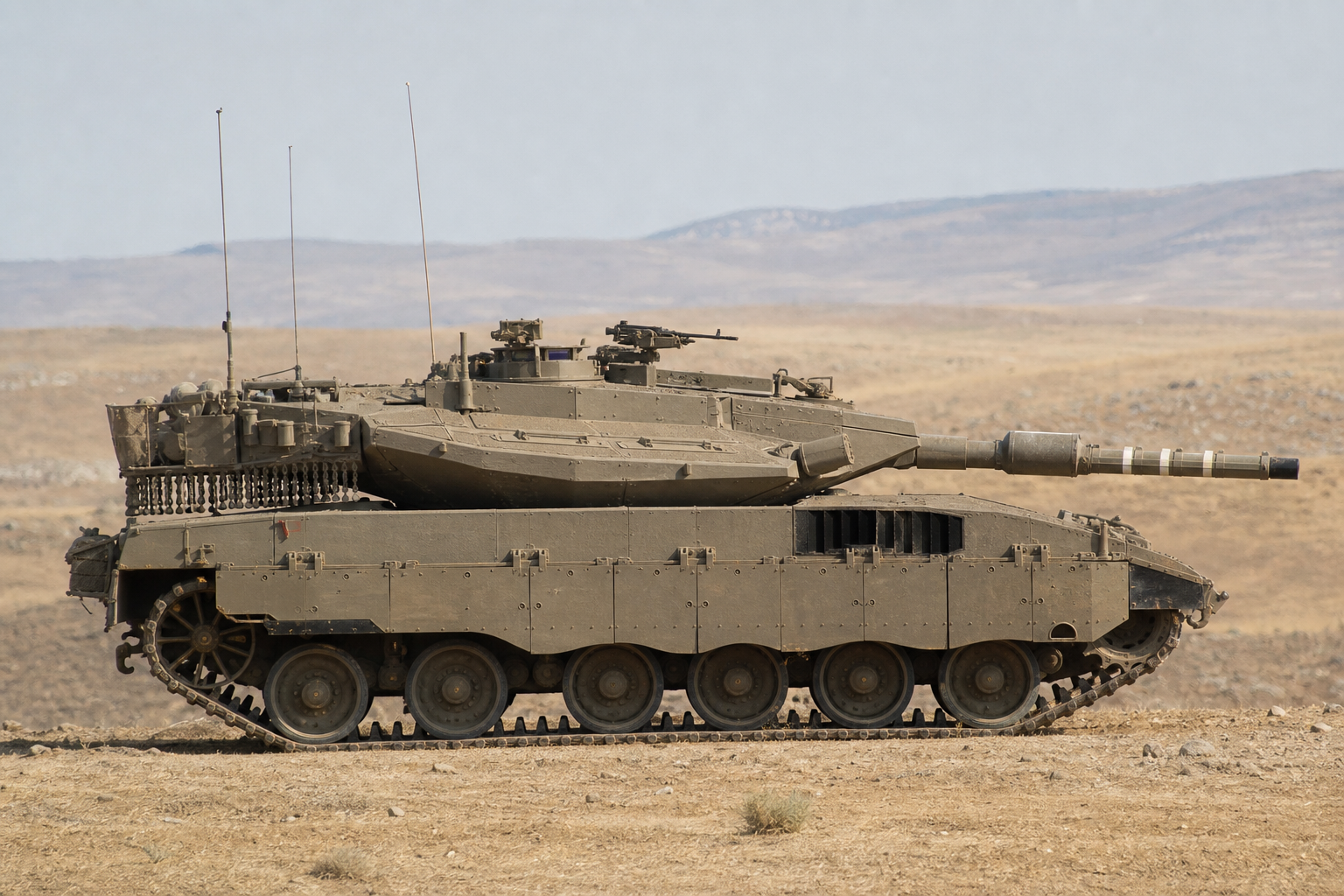 Tanque Merkava israelense visto de perfil em terreno árido durante exercício militar sem combate